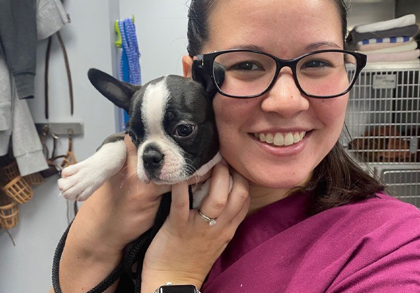 female staff member smiling and posing with black and white french bulldog puppy